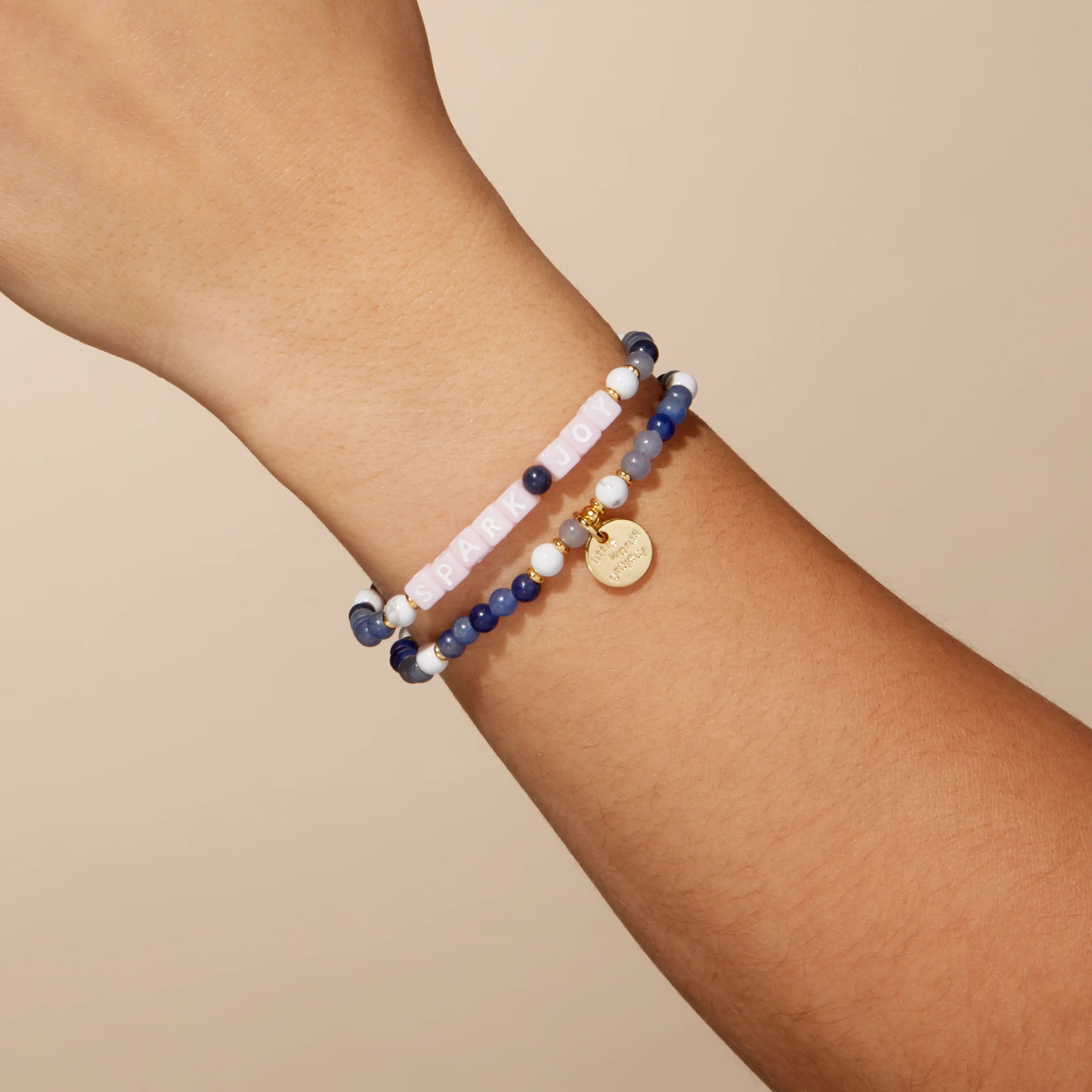 Beaded bracelets on a wrist against a beige background