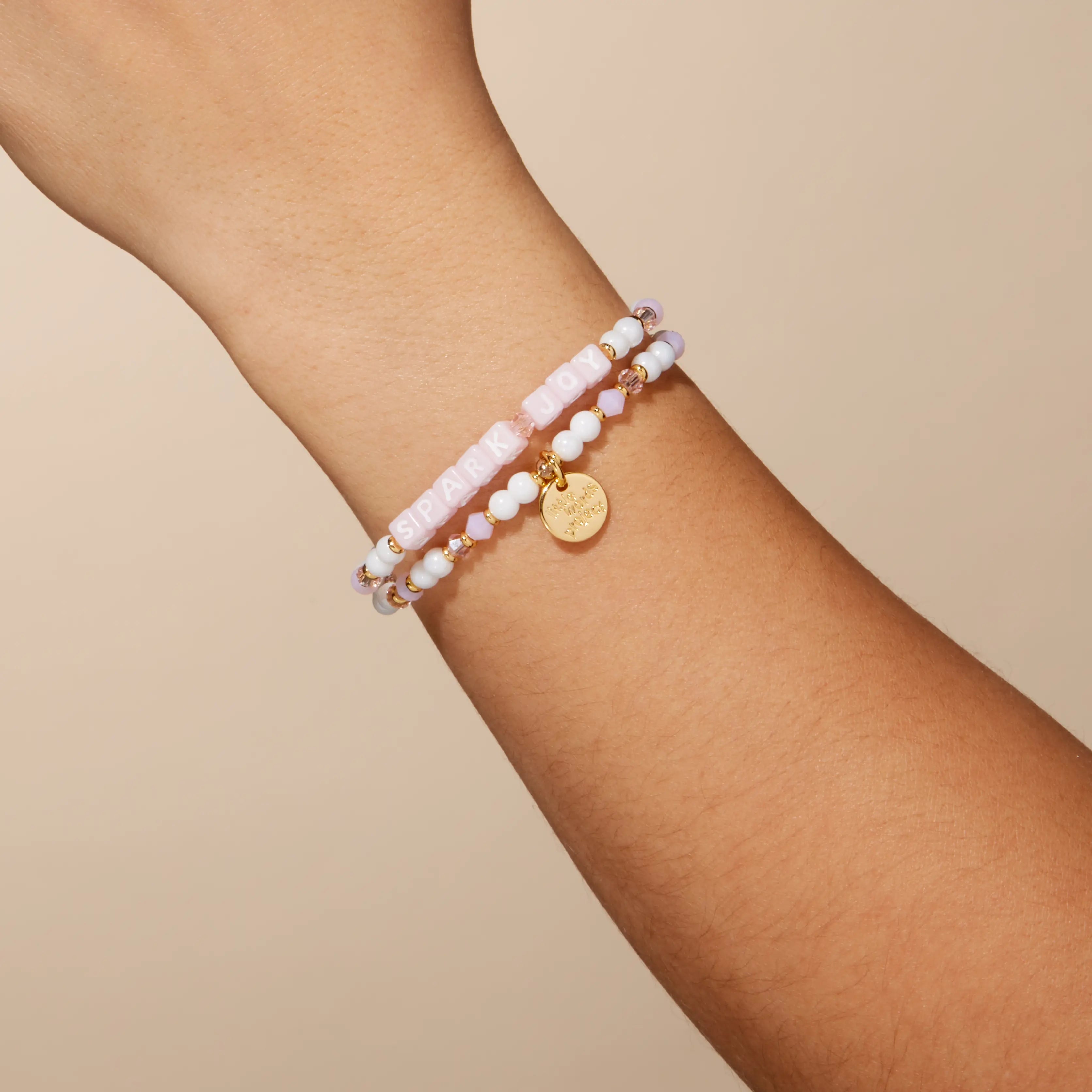 Two beaded bracelets on a wrist against a beige background