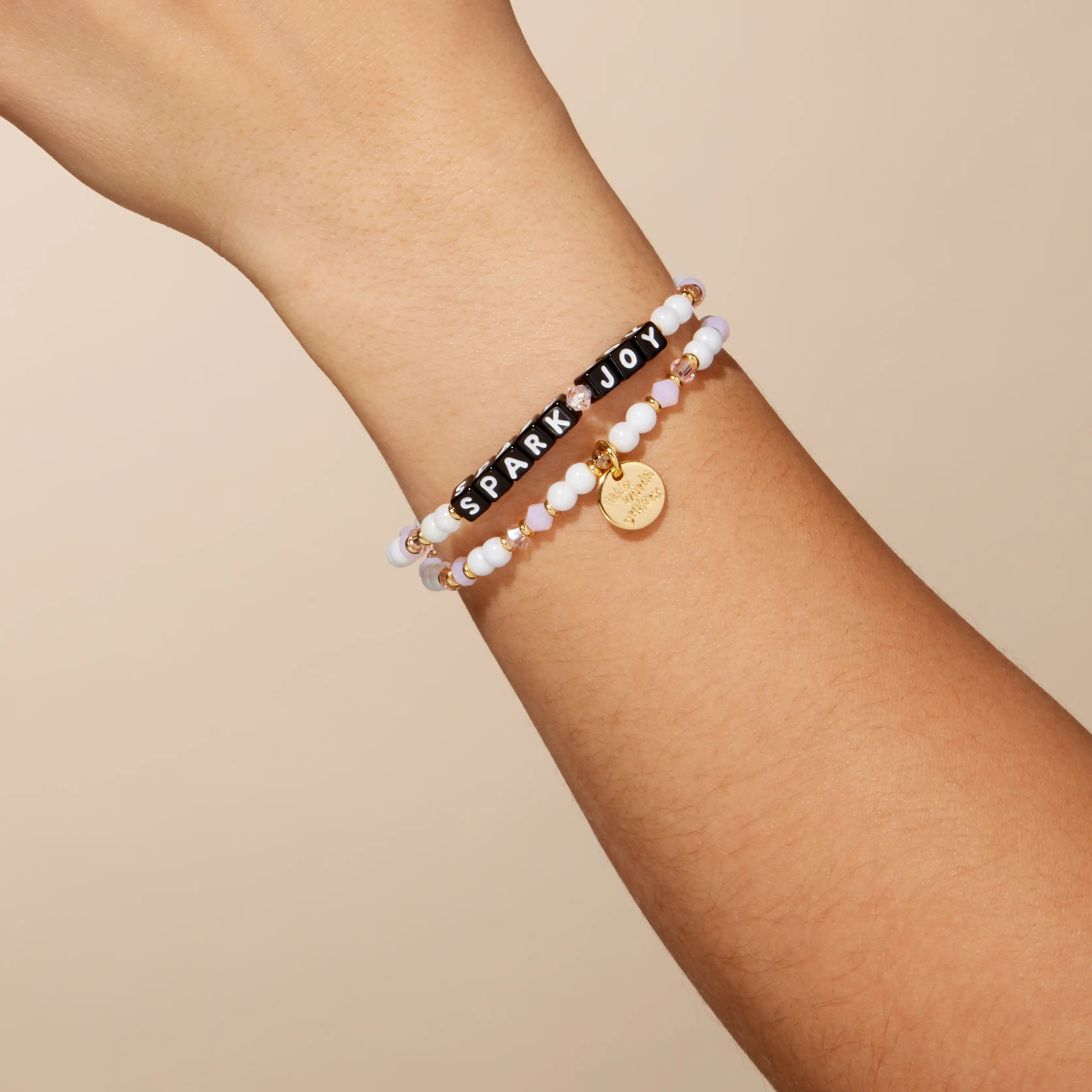 Bracelet with 'Spark Joy' on a wrist against a beige background