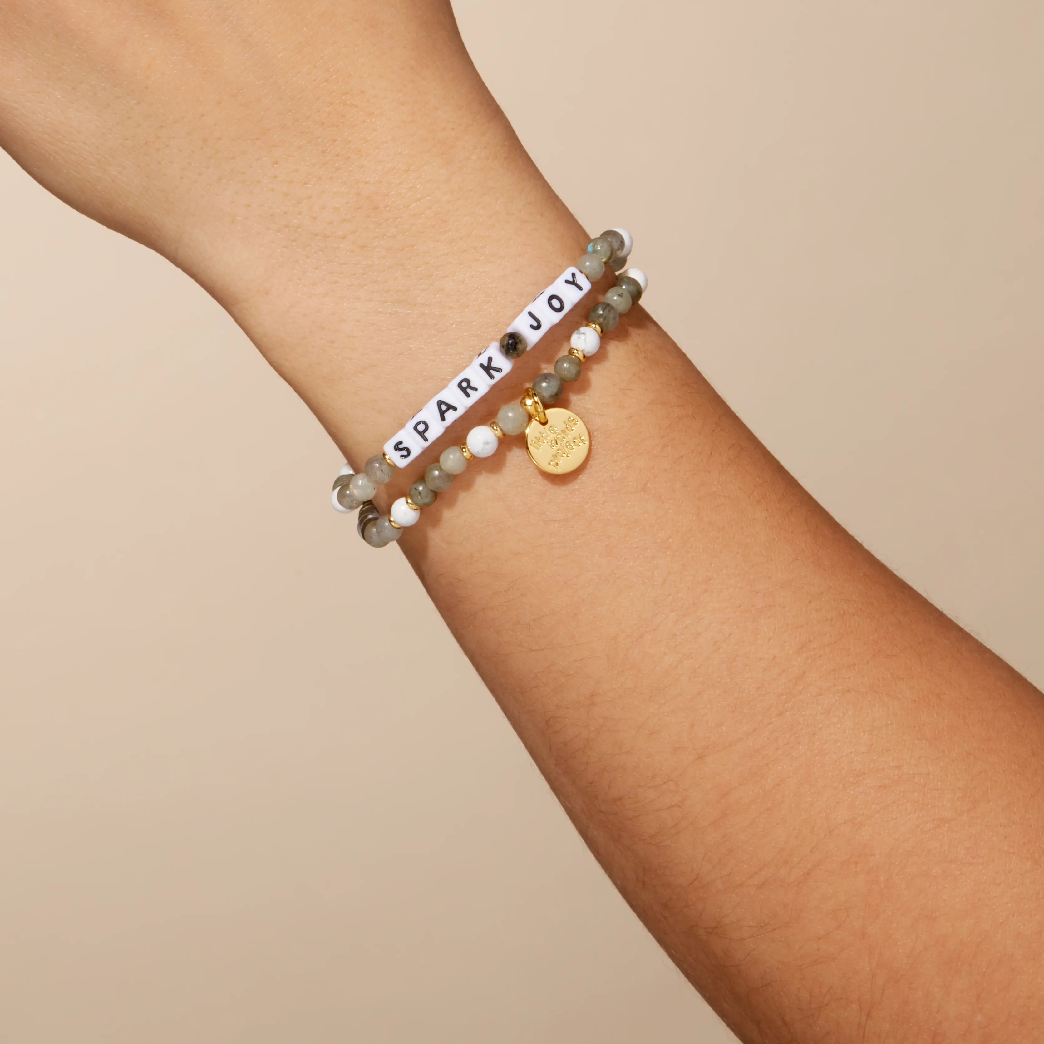Two bracelets on a wrist with a beige background