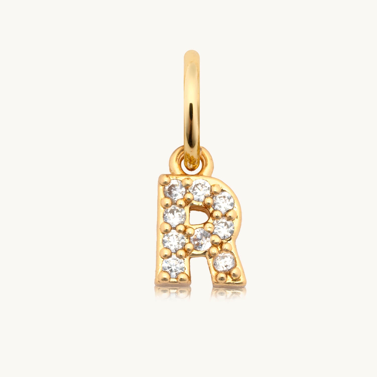 Gold pendant with letter 'R' and diamonds on a white background