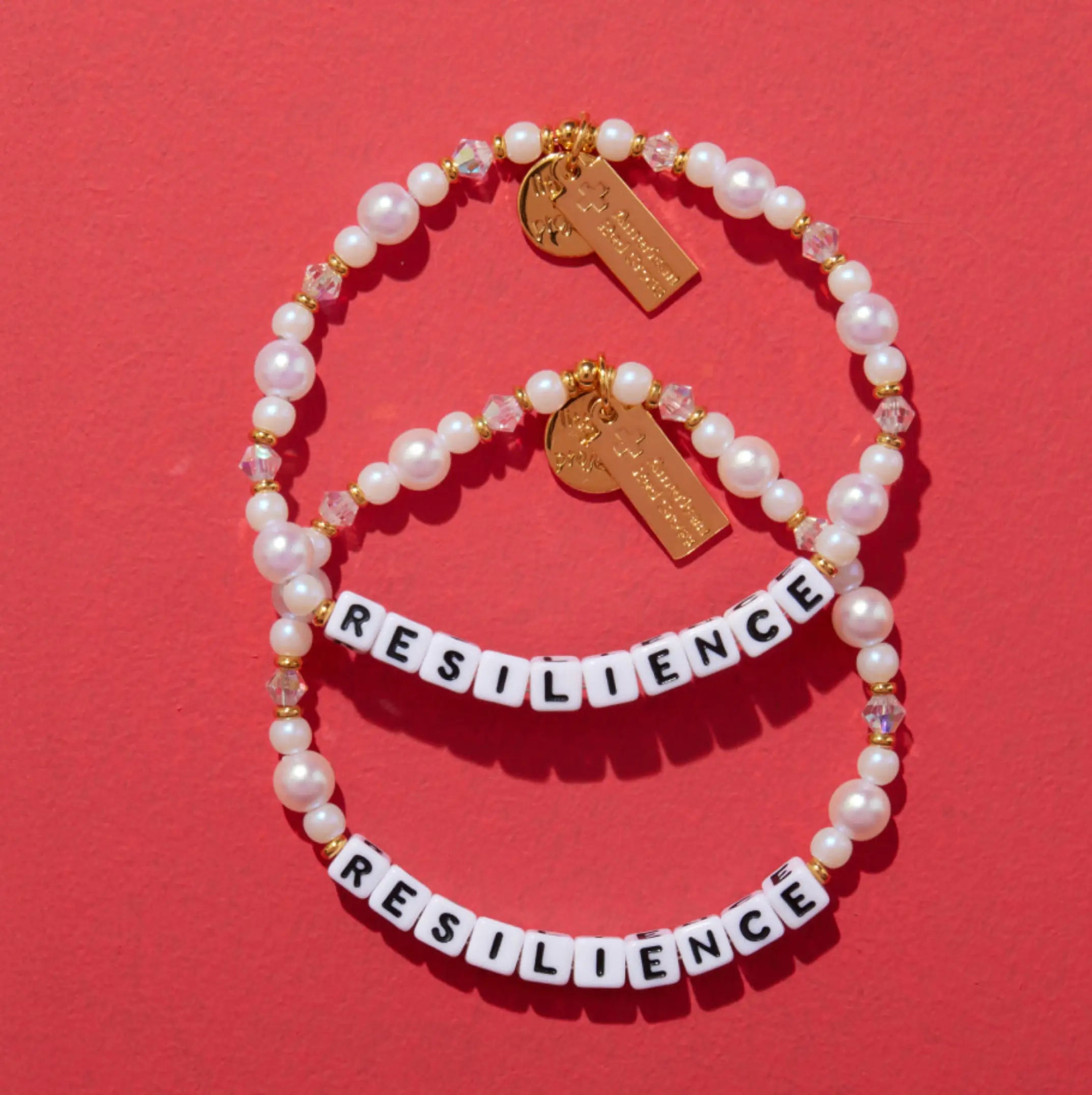 Two pearl bracelets with 'RESILIENCE' on a red background