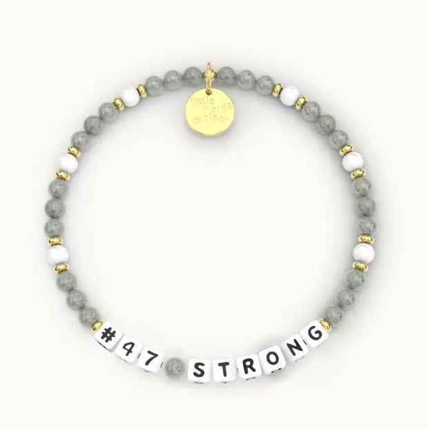 A beaded stretch bracelet featuring gray marbled beads, white spacer beads, gold-toned metal spacers, a round gold charm, and white letter beads spelling '#47 STRONG'.