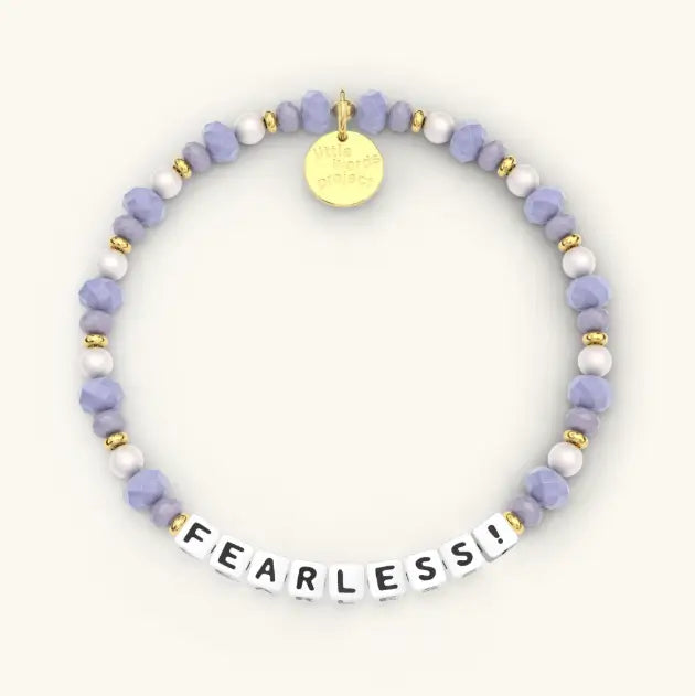 Bracelet with purple and white beads and a gold tag on a white background