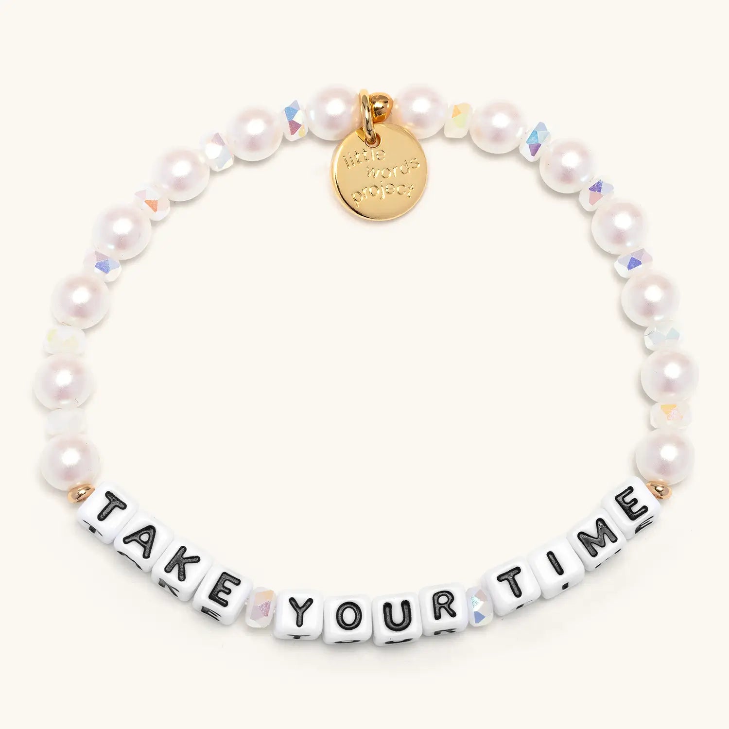 Pearl bracelet with a gold tag and letter beads spelling 'Take Your Time' on a white background