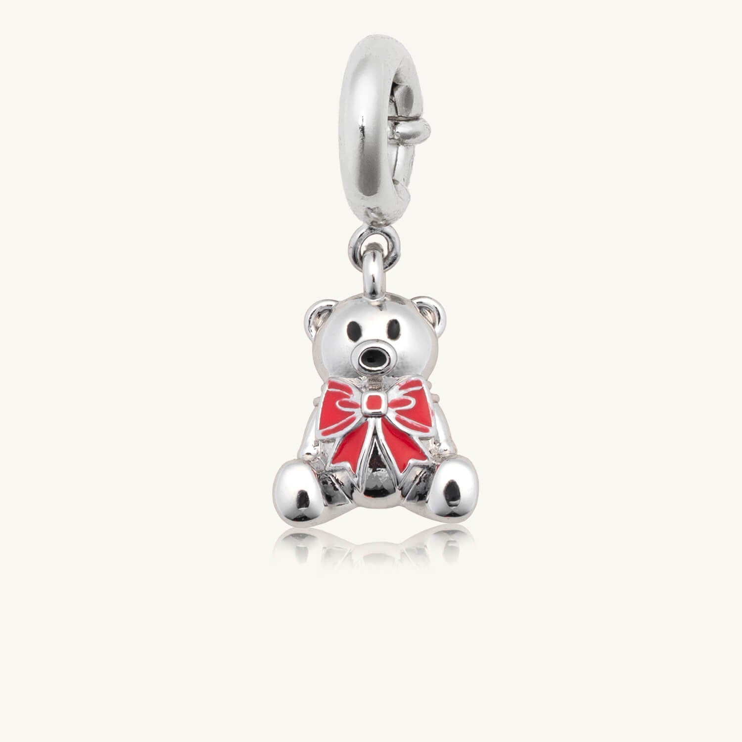 Silver teddy bear charm with a red bow on a white background