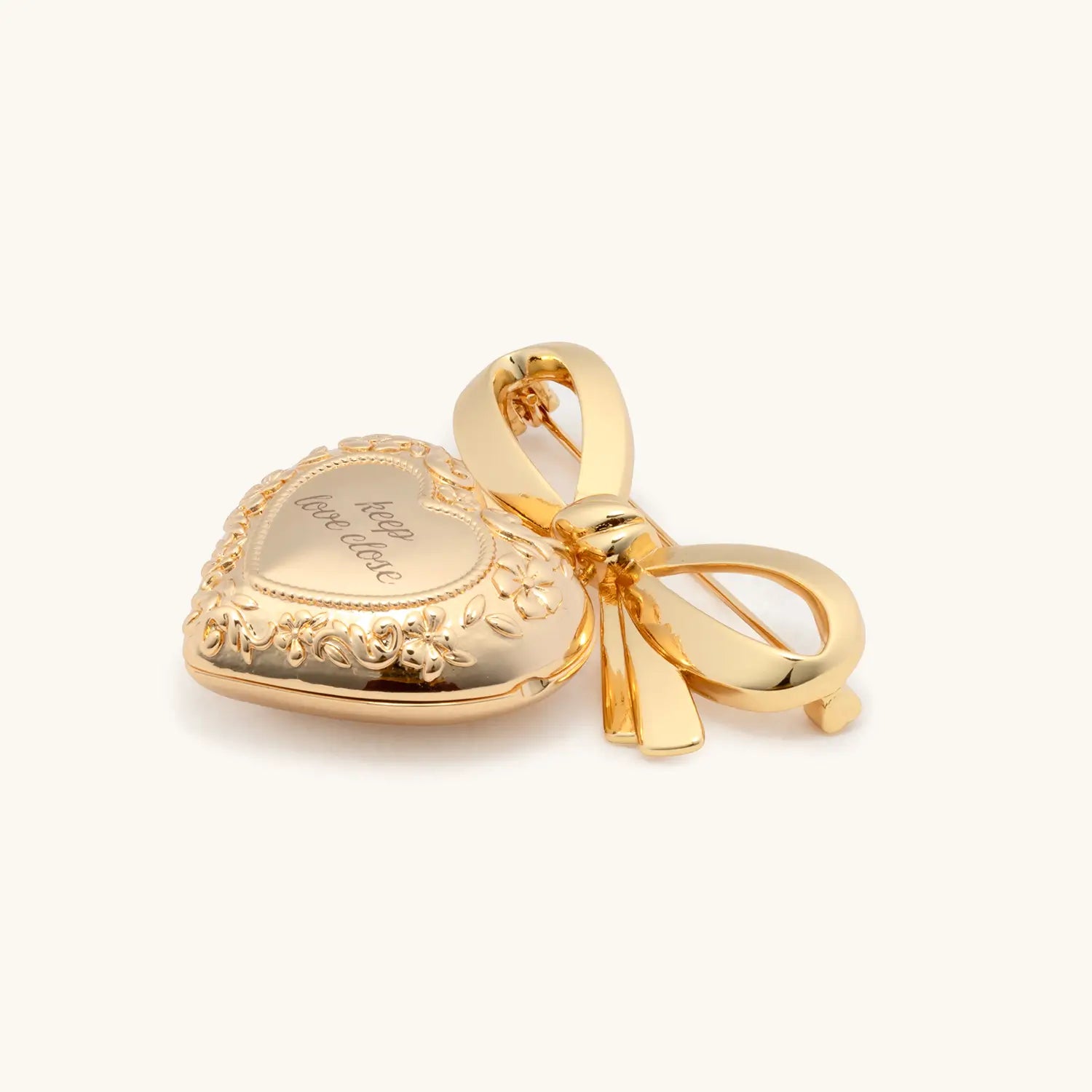 Gold heart-shaped pendant with bow on a white background