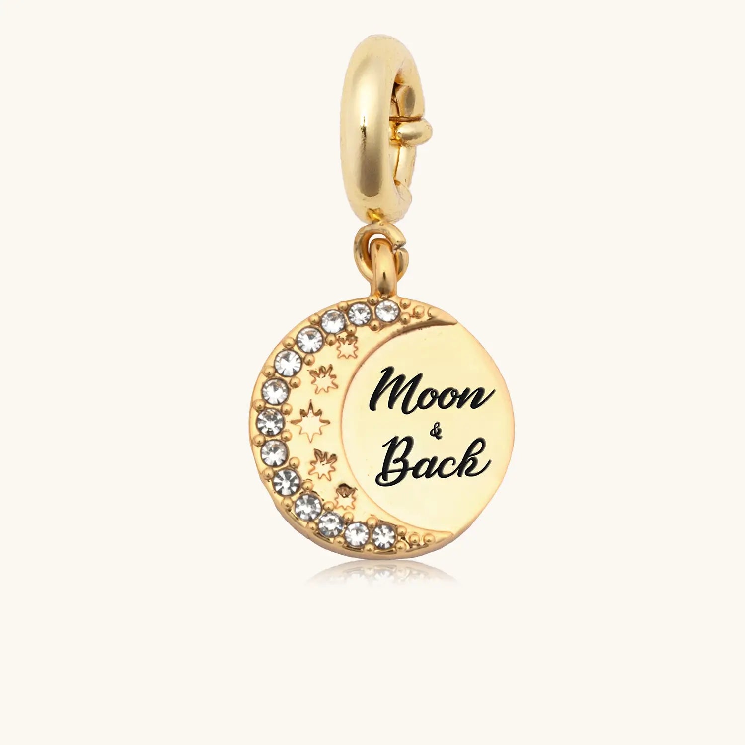 Gold charm with 'Moon & Back' engraving on a white background