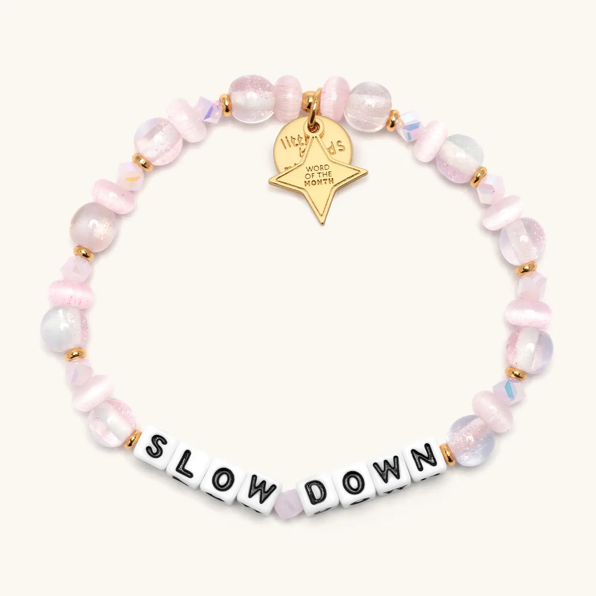 Slow Down October Word of the Month bracelet with white letter beads, pale pink glitter glass, cat eye, and iridescent crystal beads, gold spacers, and a gold star Word of the Month charm, flat-lay
