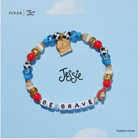 Be Brave Toy Story bracelet with a gold charm on a blue background with a Jessie signature