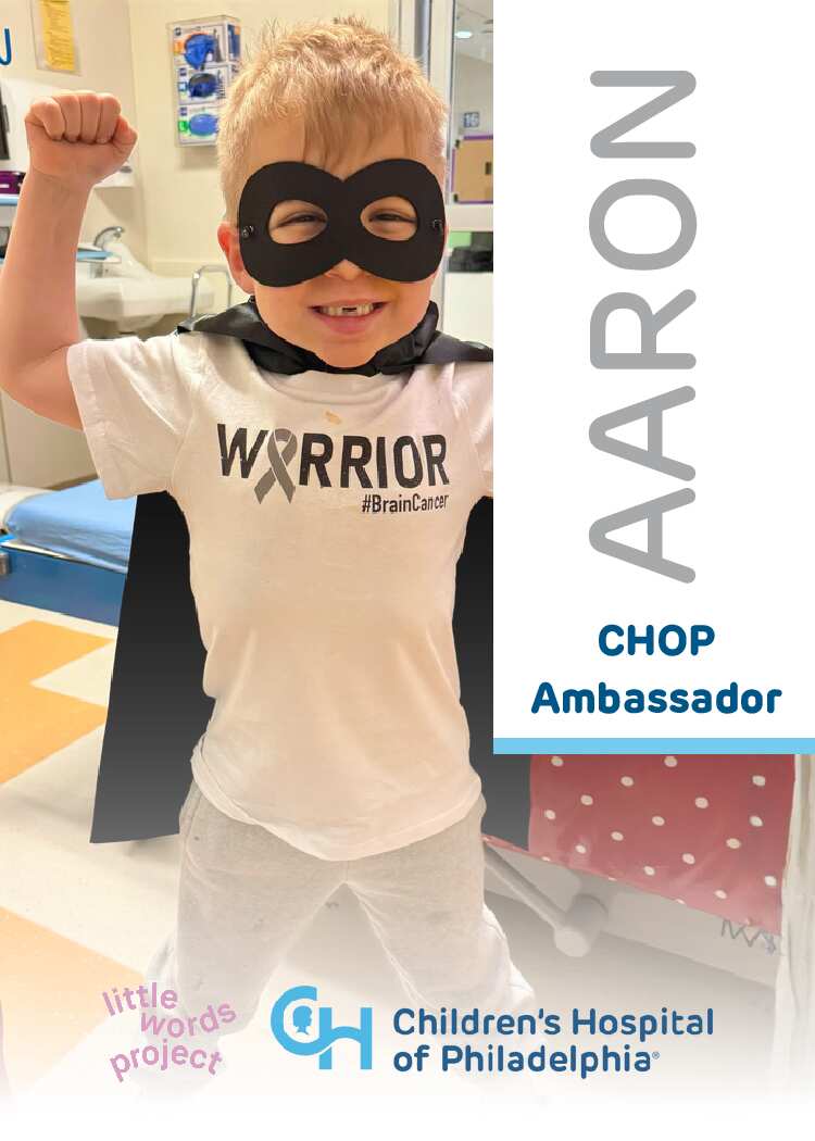 Child wearing a 'Warrior' shirt with a cape and mask, standing in a hospital room, with 'Children's Hospital of Philadelphia' branding.