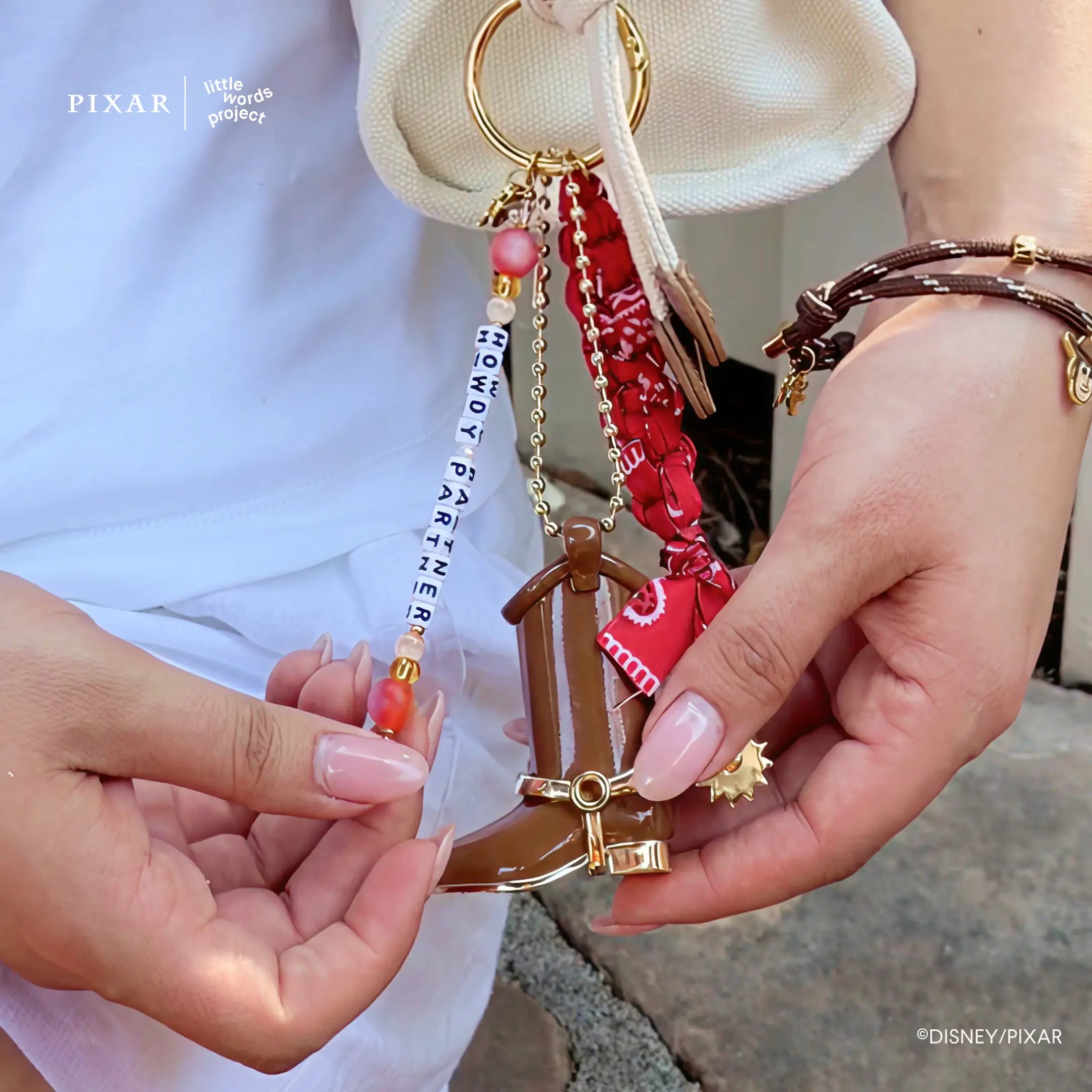Howdy Partner Toy Story bag charm clipped to a bag and held in hand, lifestyle shot