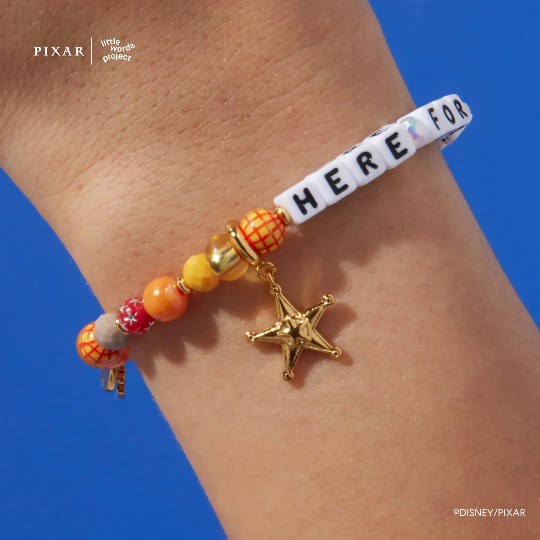 Reach for the Sky charm set, gold sheriff badge star charm on a Here For You Toy Story bracelet, on a wrist