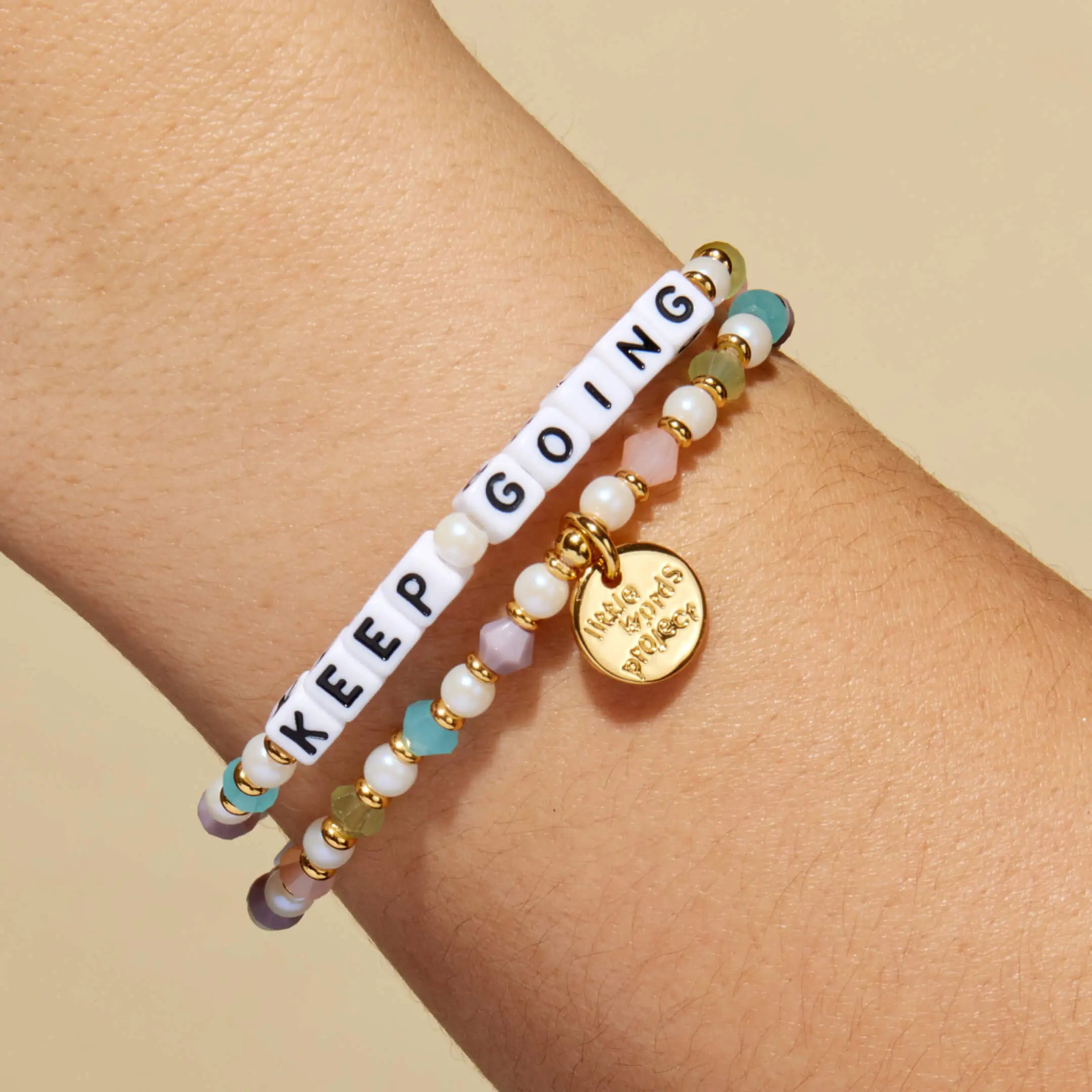 Bracelet with 'KEEP GOING' message on a wrist against a beige background