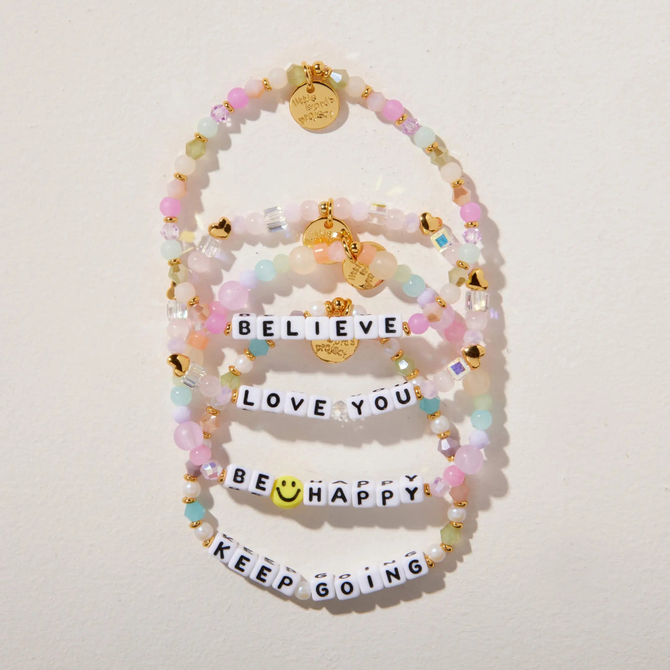 Set of colorful beaded bracelets with motivational phrases on a light background