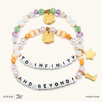 To Infinity and Beyond Toy Story set, two bracelets spelling TO INFINITY and AND BEYOND with gold star and rocket charms, flat lay