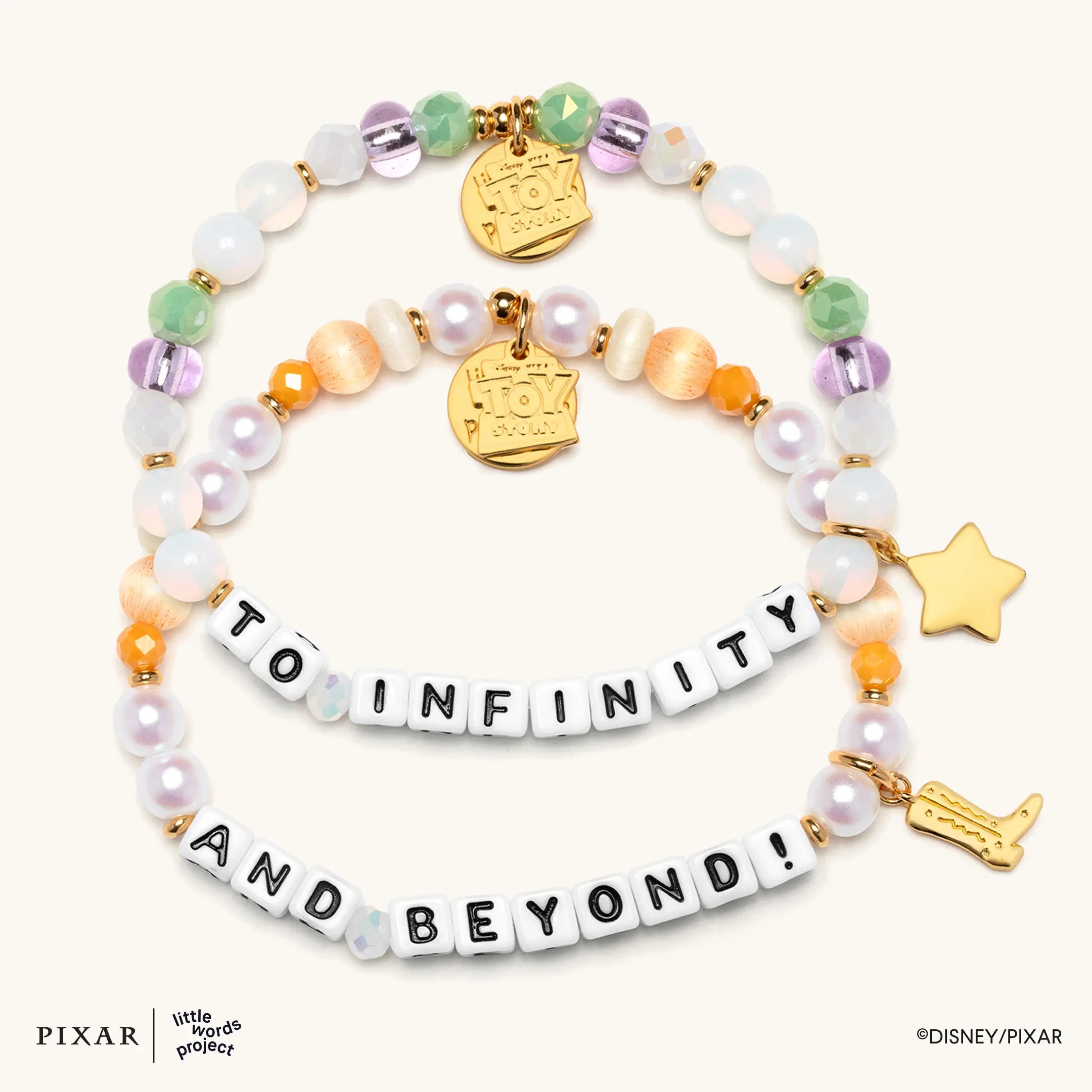 To Infinity and Beyond Toy Story set, two bracelets spelling TO INFINITY and AND BEYOND with gold star and rocket charms, flat lay