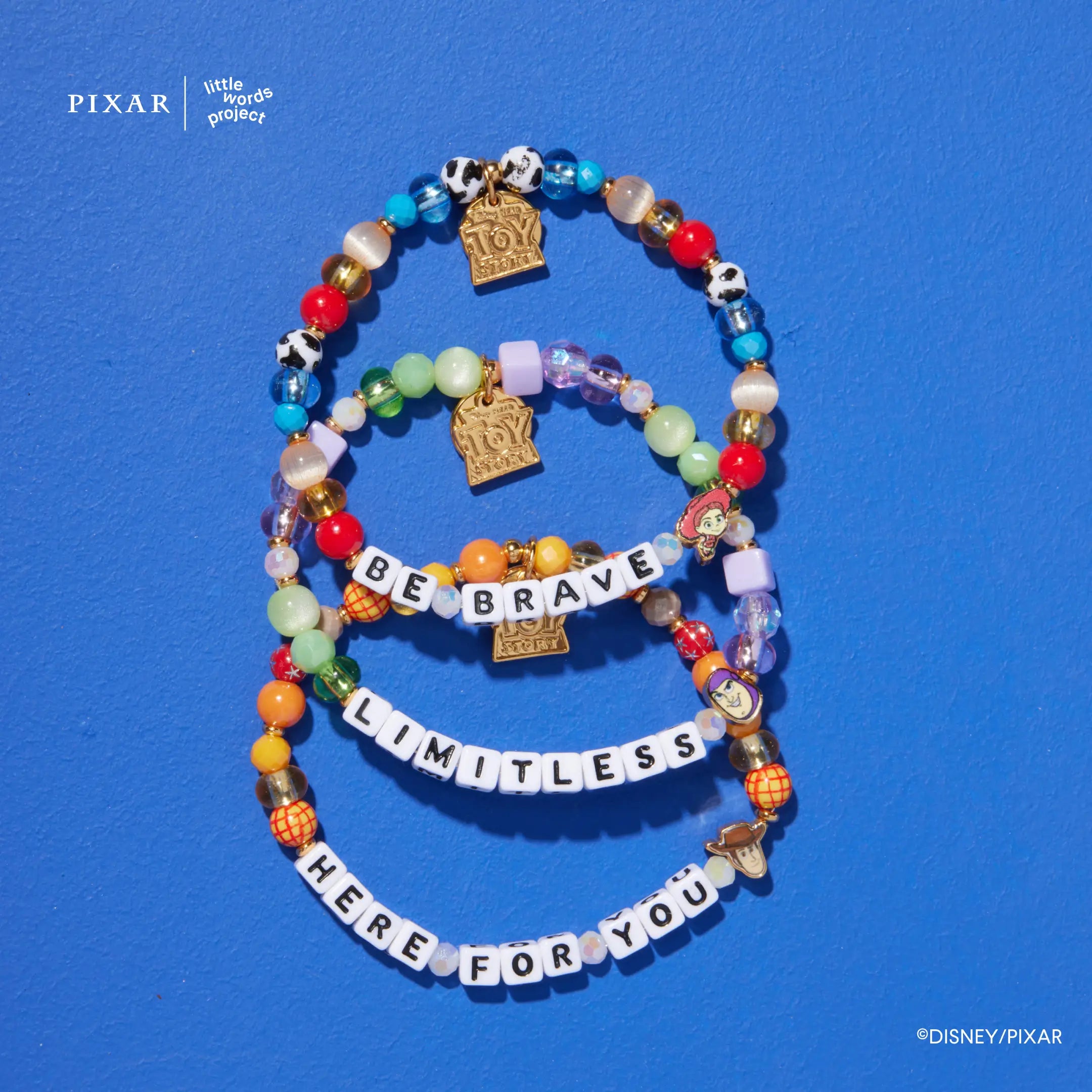 You've Got a Friend three-bracelet Toy Story set with gold charms, flat lay on blue