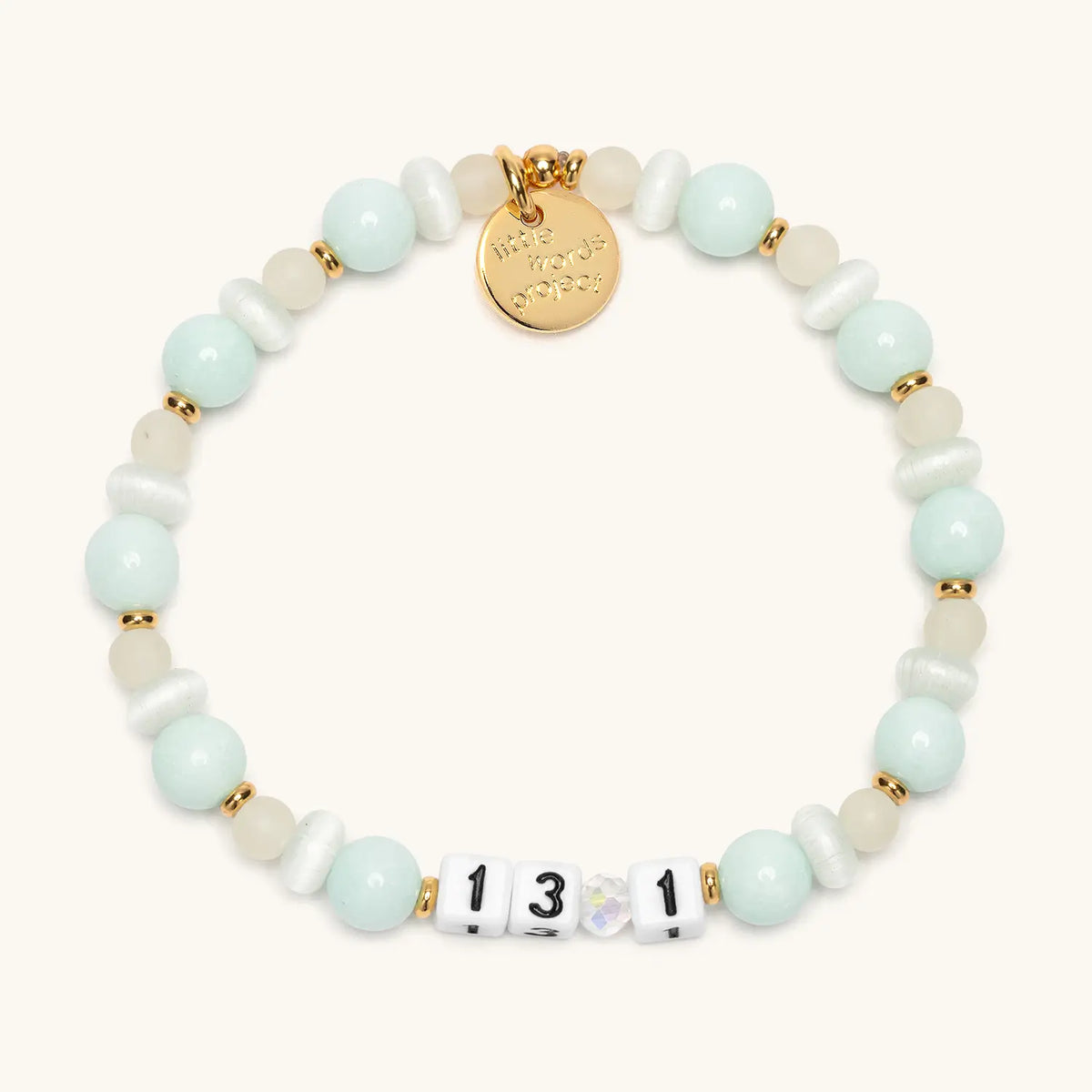 13.1 bracelet in the Sea Breeze bead pattern, white number beads with mint blue stone beads, white cat eye beads, frosted glass beads, and an iridescent crystal with gold accents, flat-lay on cream background