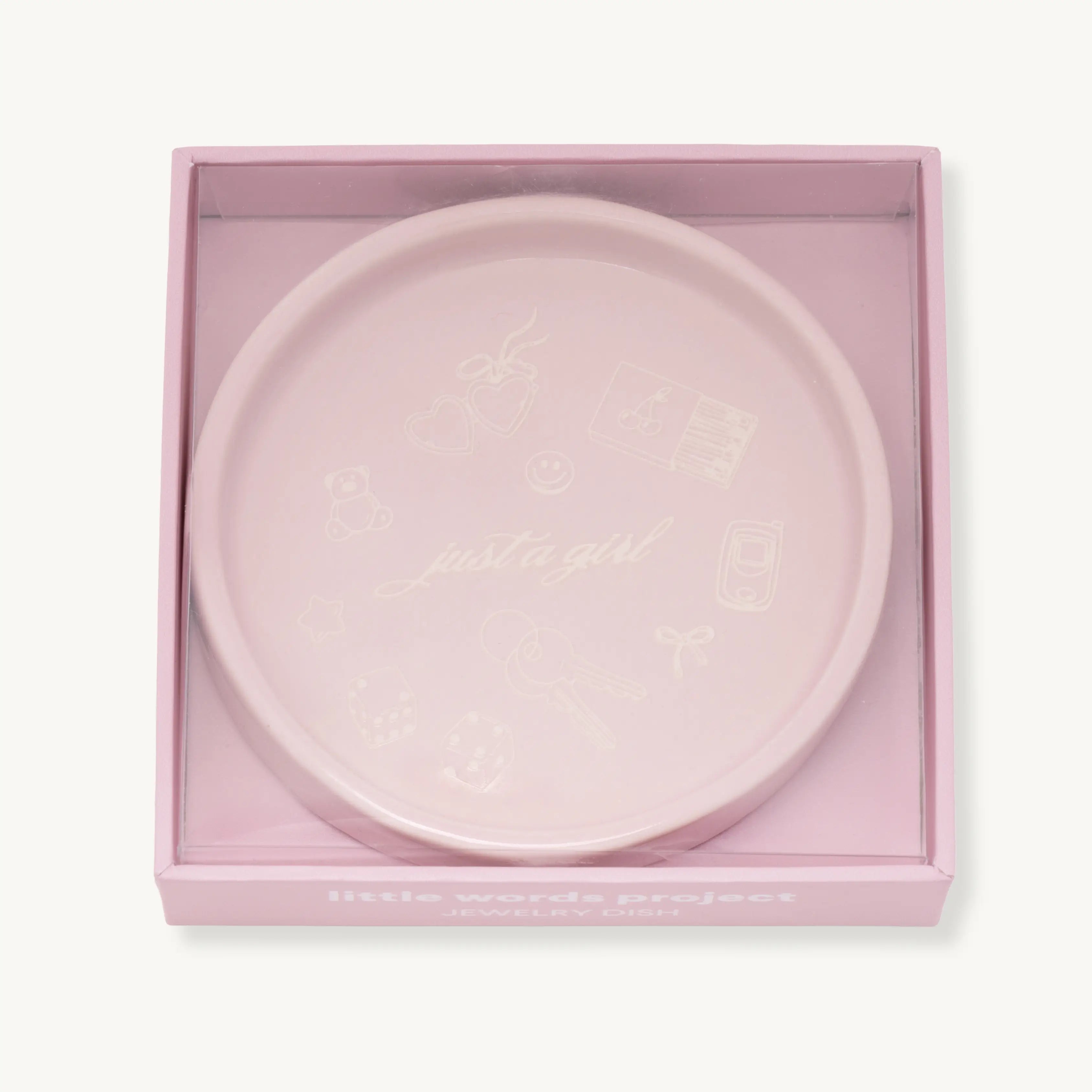 Pink decorative jewelry dish with 'Just a Girl' text in a matching box on a white background