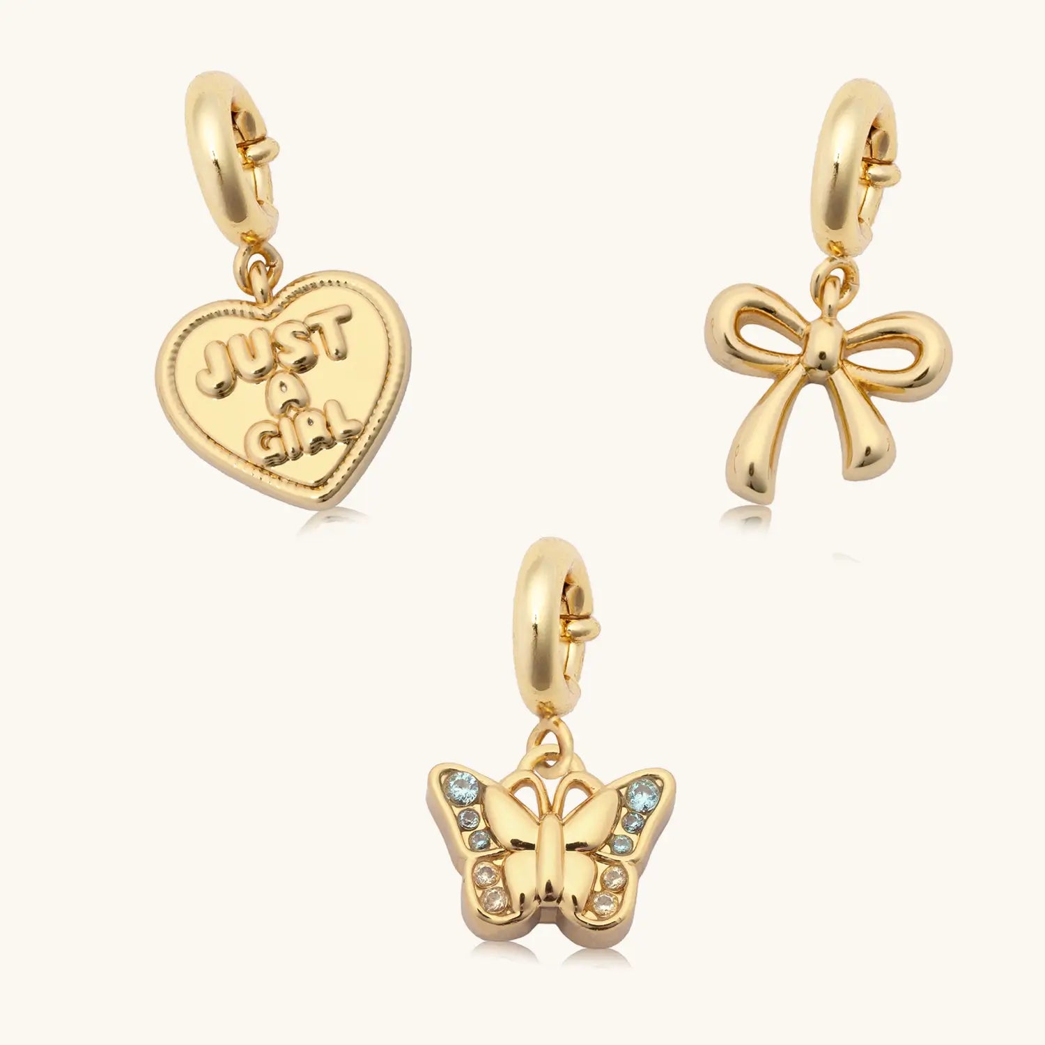 Just A Girl Charm Set with gold heart, bow and gemstone butterfly charms, flat lay
