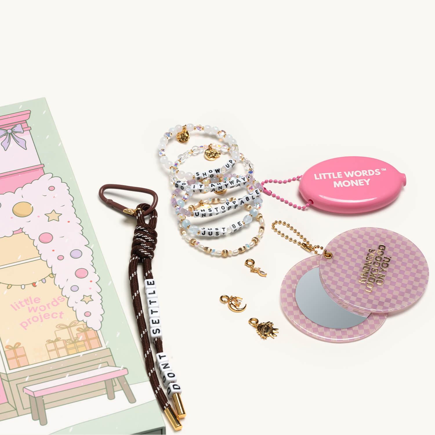 Collection of accessories including a pen, bracelets, and a compact mirror on a white background.