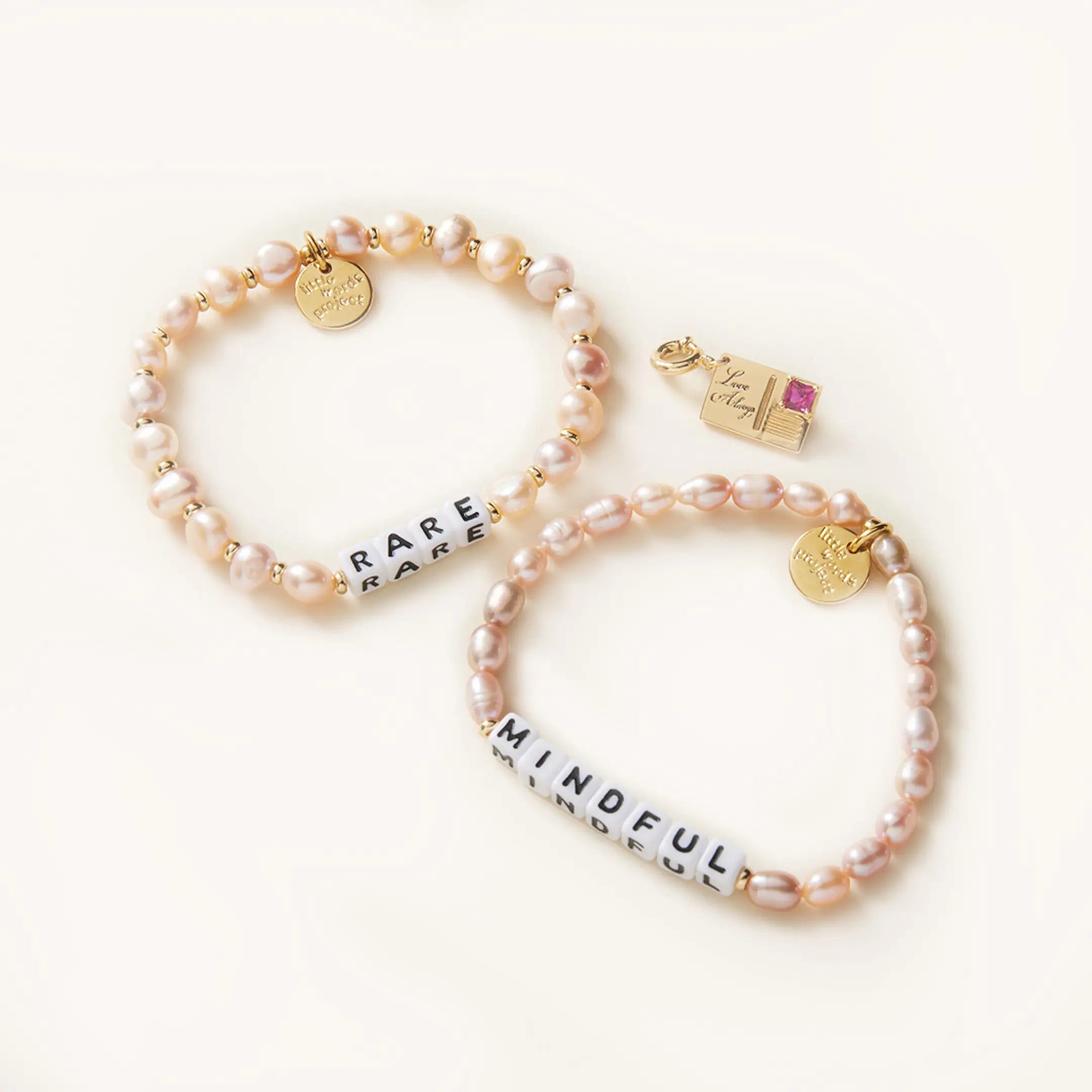 Two pearl bracelets with gold charms on a white background
