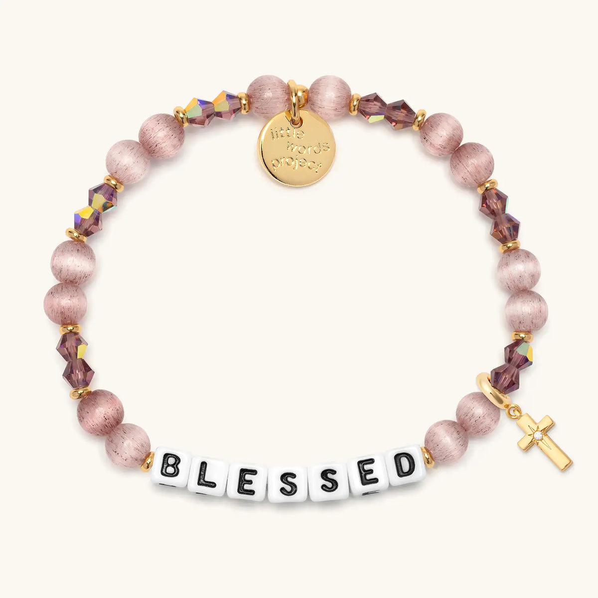 Blessed bracelet in the Holiday Spritz bead pattern with white letter beads, gold puffy cross charm with a clear CZ stone, flat-lay on cream background