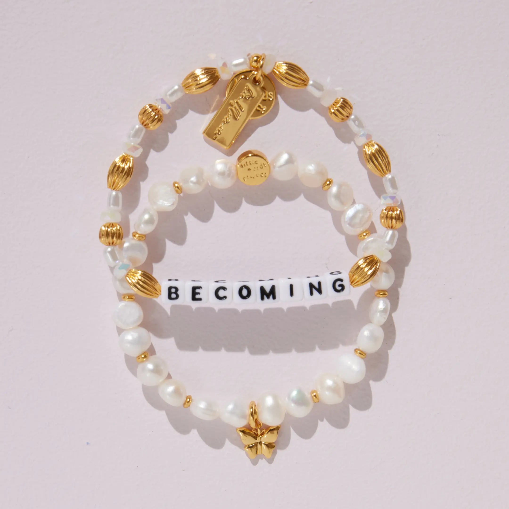 Becoming Bracelet Set- Nika Diwa on-model wrist detail, Becoming bracelet and Butterfly Pearl Bracelet Base with gold butterfly charm stacked