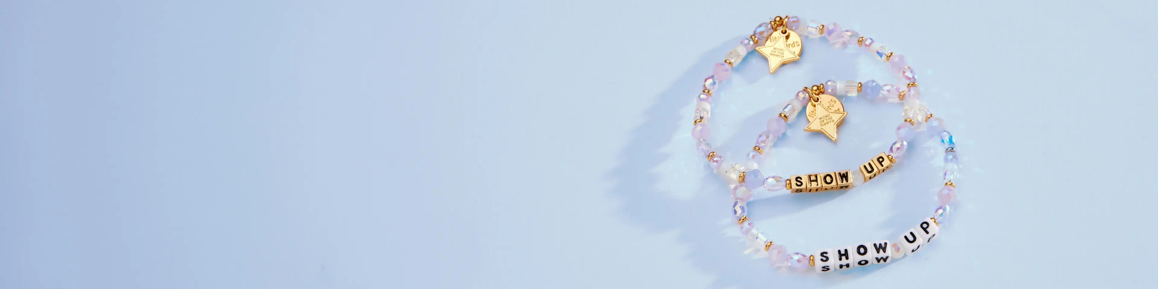 Two SHOW UP bracelets on a light blue background