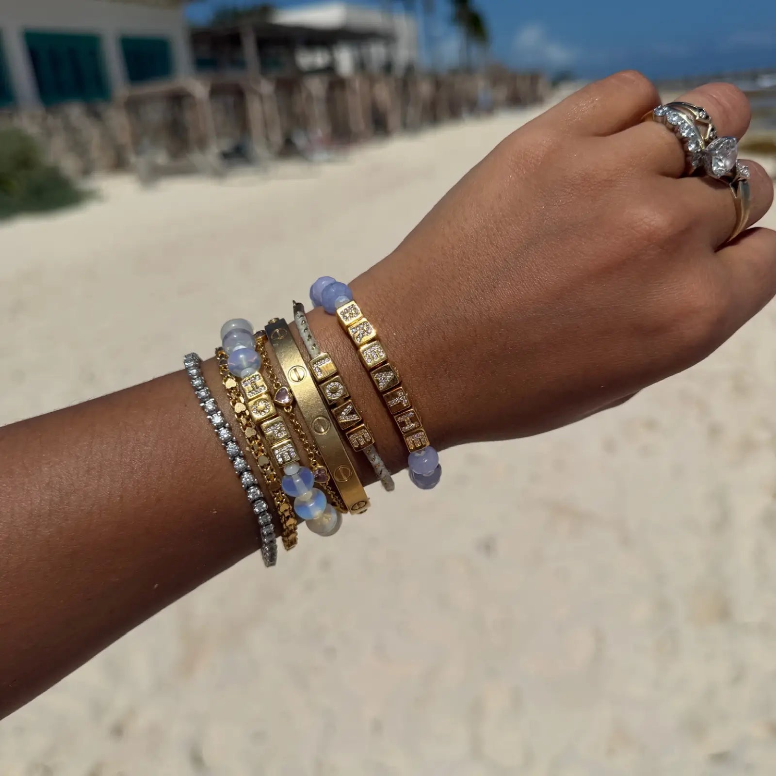 Hand wearing multiple bracelets on a beach