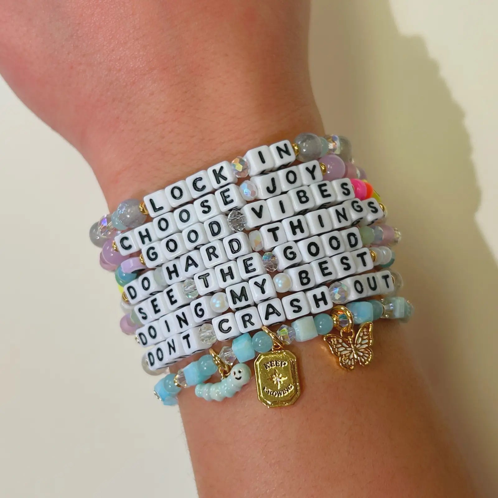 Bracelet with motivational phrases on a wrist against a neutral background