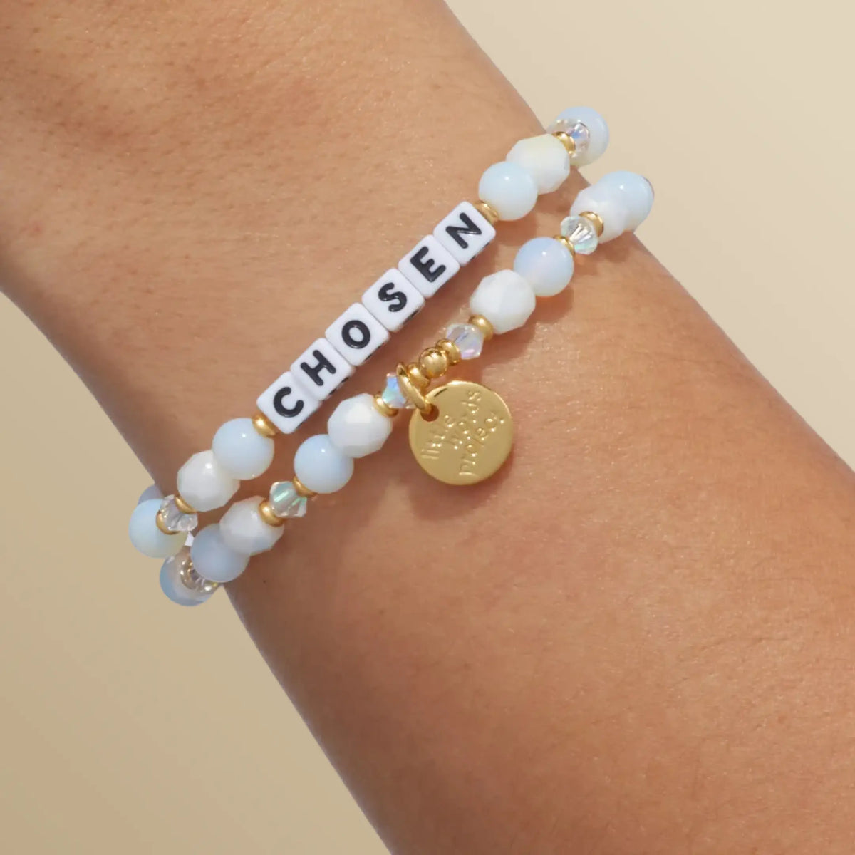 Chosen bracelet in the Snow Fantasy bead pattern with white letter beads, stacked with a second bracelet, on-model wrist shot on warm neutral background
