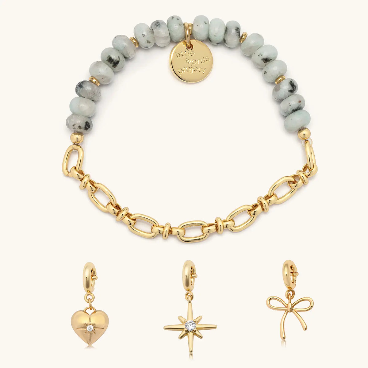 Smoky Ink Charm Bracelet Set, half beaded, half chain bracelet base in speckled mint green stone and gold chain shown with gold cz heart, starburst, and bow charms, flat-lay on cream background