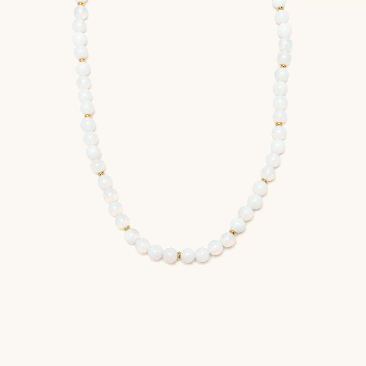 Opal Light Necklace, glowing white round beads with small gold spacer beads, flat-lay on cream background