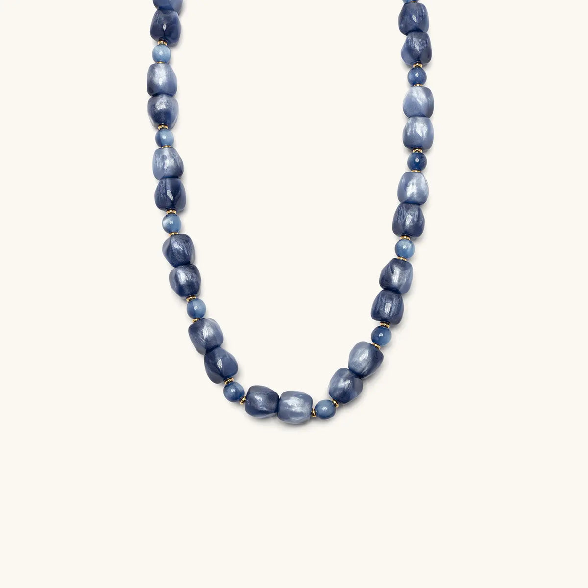Radio Fever Necklace, shimmery denim blue organic shaped beads with small blue round beads, flat-lay on cream background