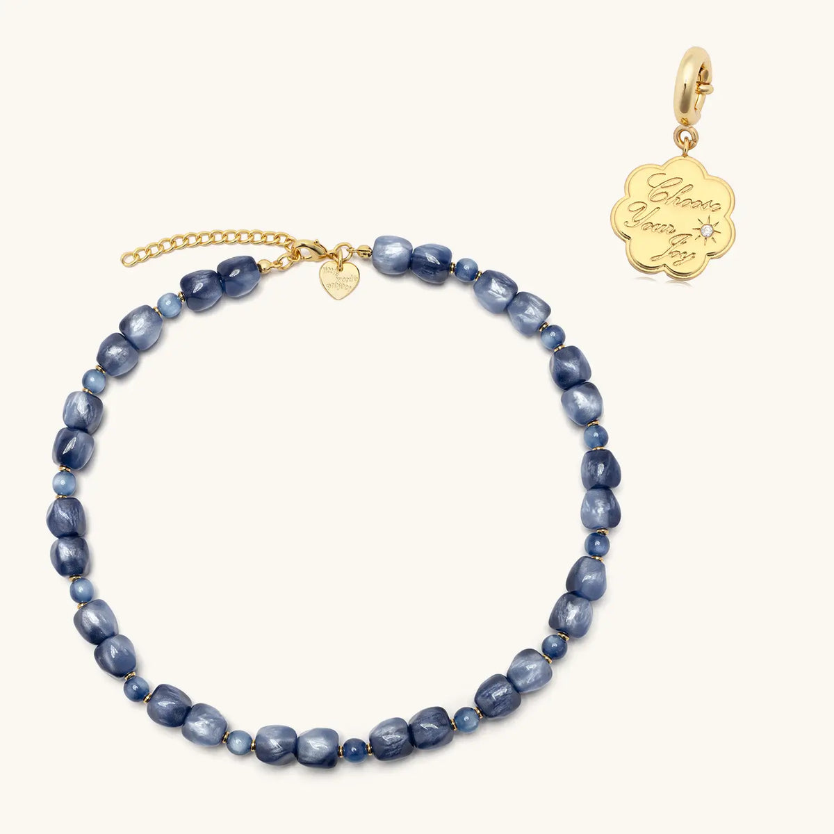 Radio Fever Charm Necklace set, shimmery blue beaded Radio Fever necklace with a gold Choose Your Joy coin charm shown beside it, flat-lay on cream background