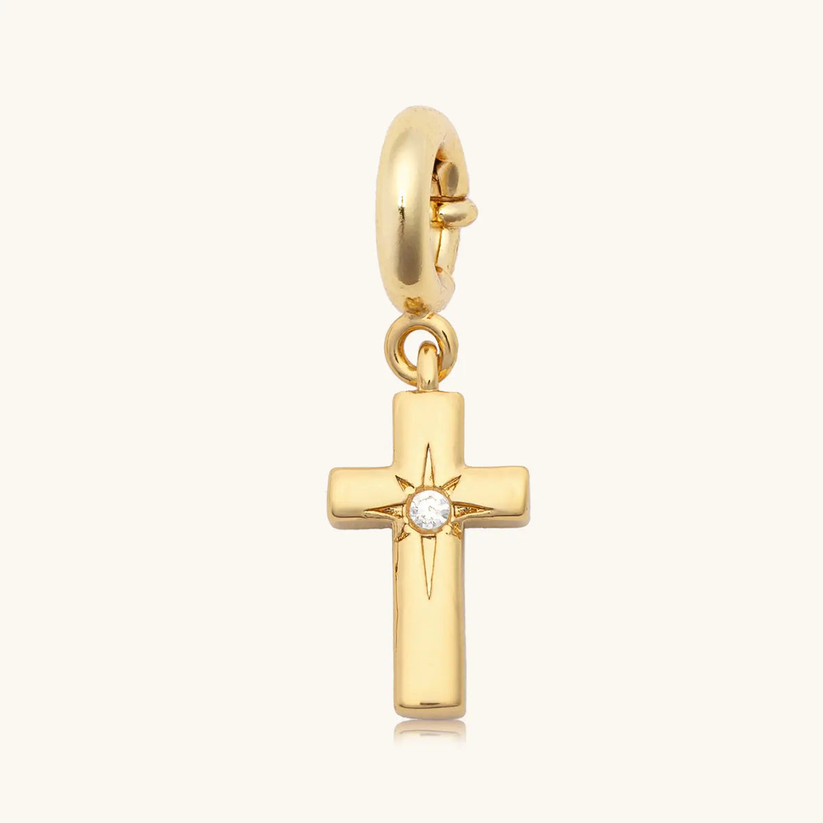 Puffy Cross charm option for the God is Good bracelet, gold puffy cross with an etched starburst and a clear CZ stone on a gold spring ring clasp, on cream background