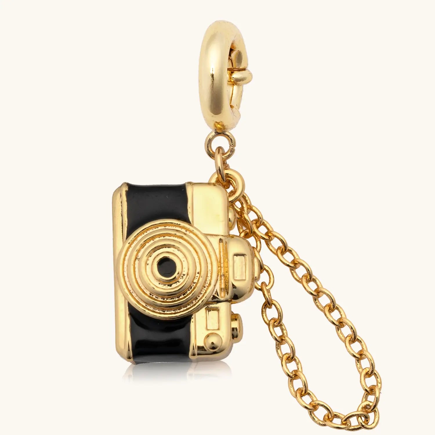Gold camera charm with a chain on a white background