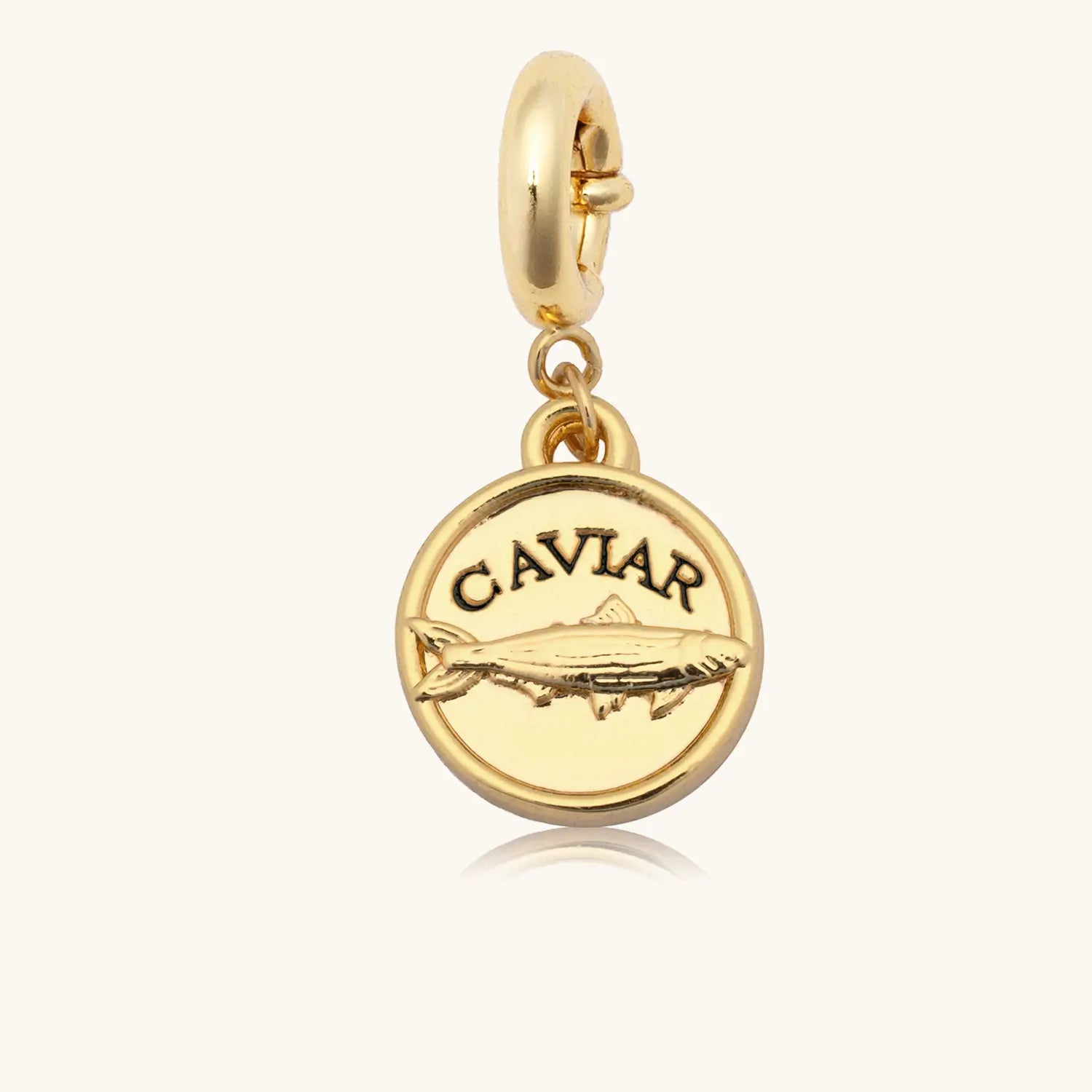 Gold charm with 'CAVIAR' text on a white background