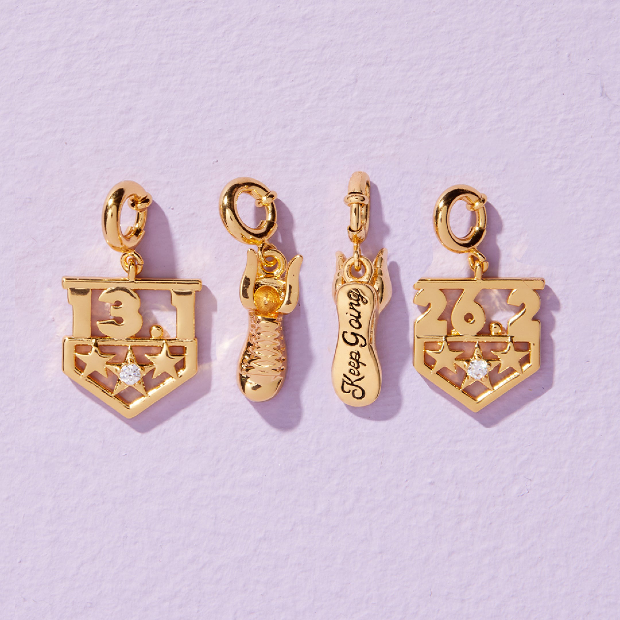 Four gold charms on a light purple background