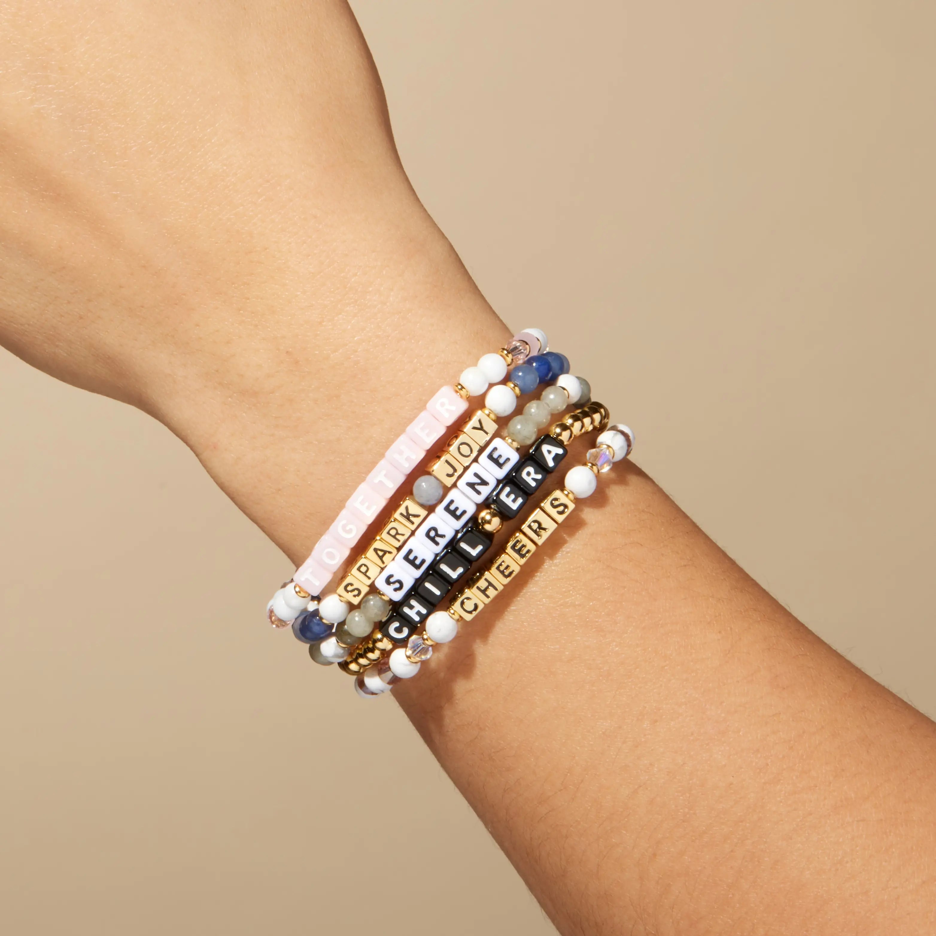 Stack of beaded bracelets on a wrist with a beige background