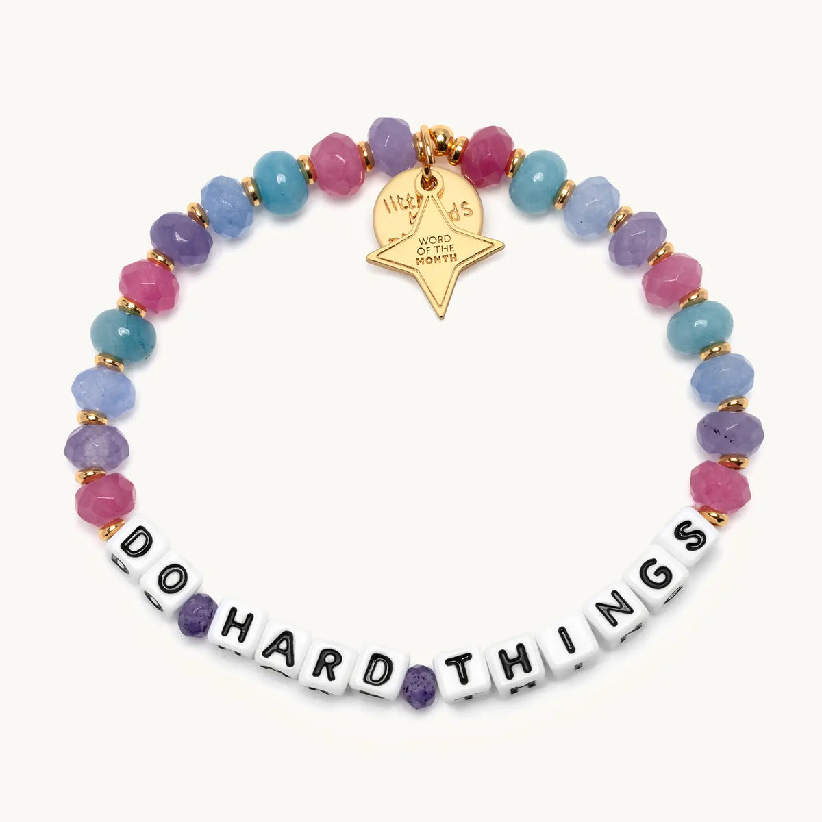 Do Hard Things September Word of the Month bracelet with white letter beads, pink, purple, blue and teal faceted beads, gold spacers and a gold star Word of the Month charm, shown flat on a cream background