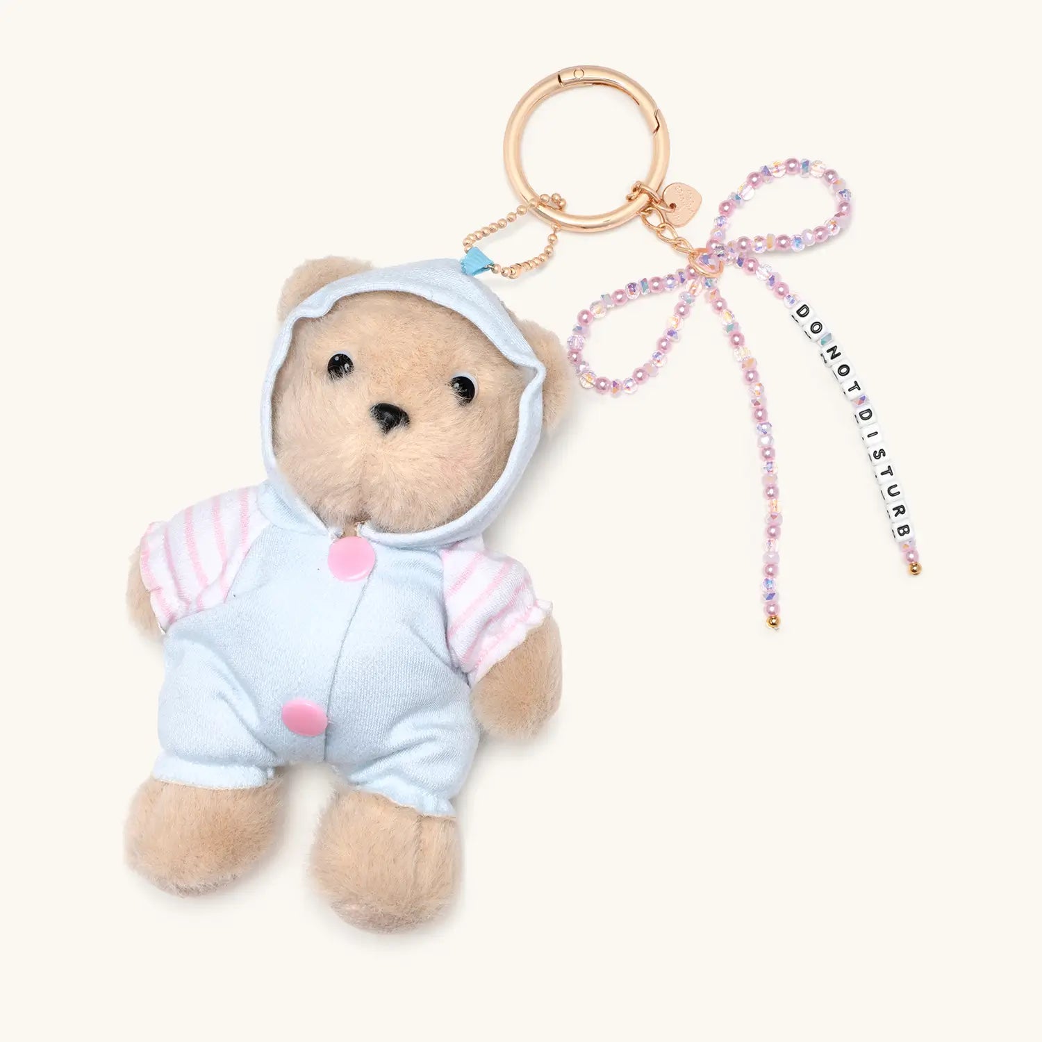 Do Not Disturb plush bear bag charm in blue onesie with beaded bow, flat lay