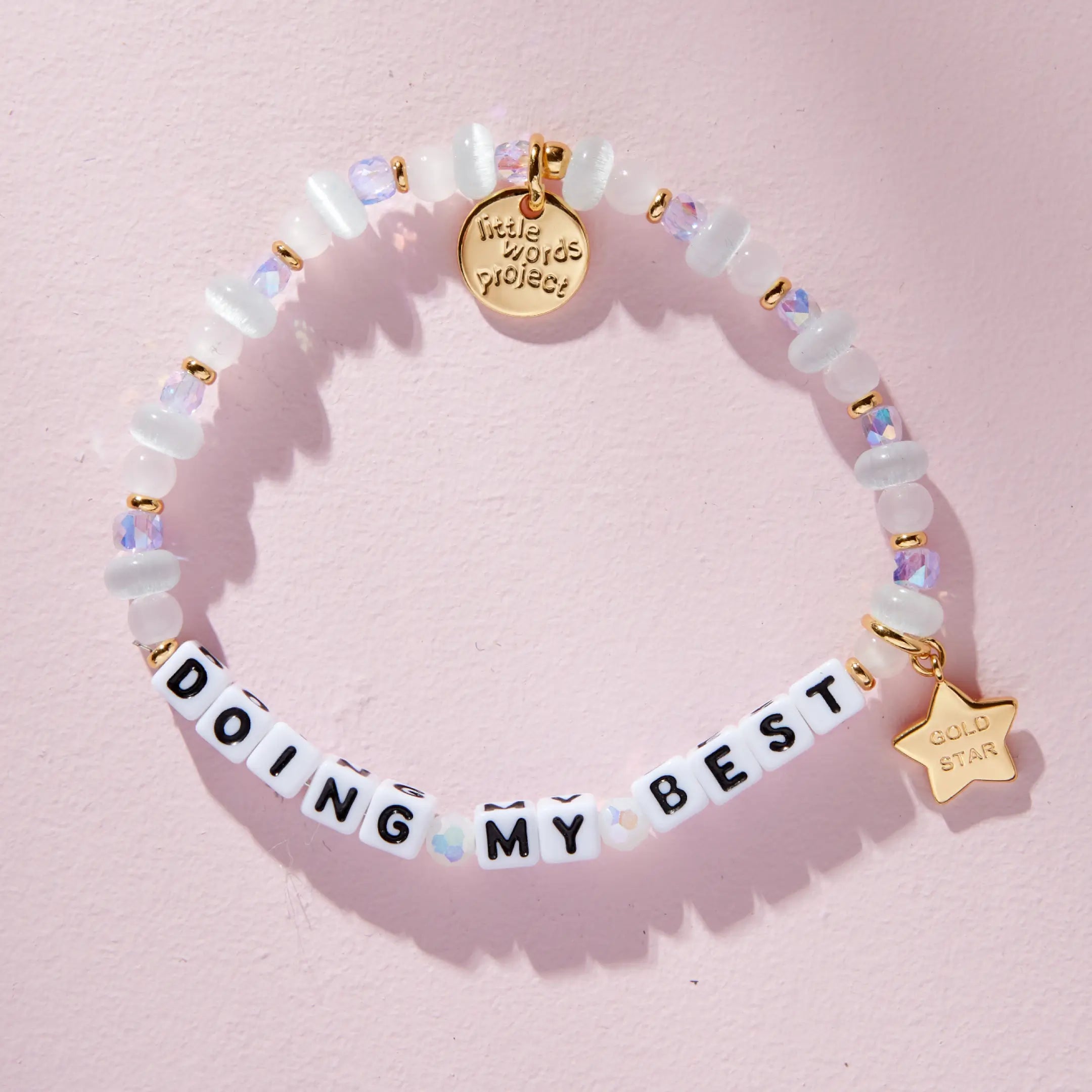 Doing My Best bracelet with pastel beads and gold star charm, flat lay on pink