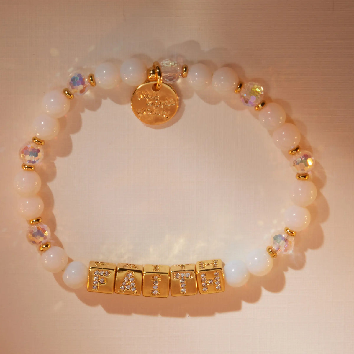 BOLDER Faith Bracelet in the Icicle Energy bead pattern with gold CZ letter blocks, flat-lay on warm neutral background with soft light