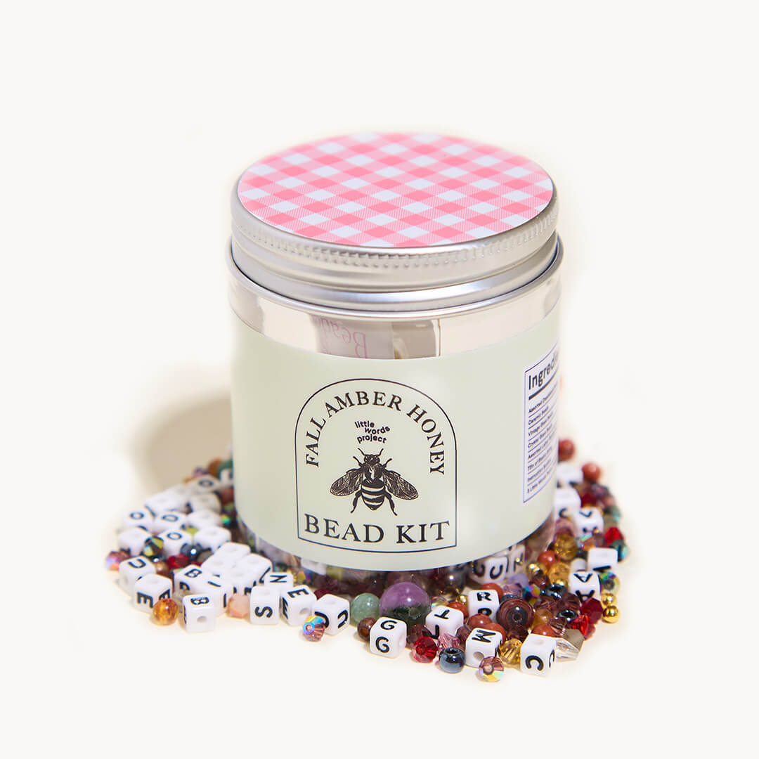 Bead kit with colorful beads and a labeled container on a white background