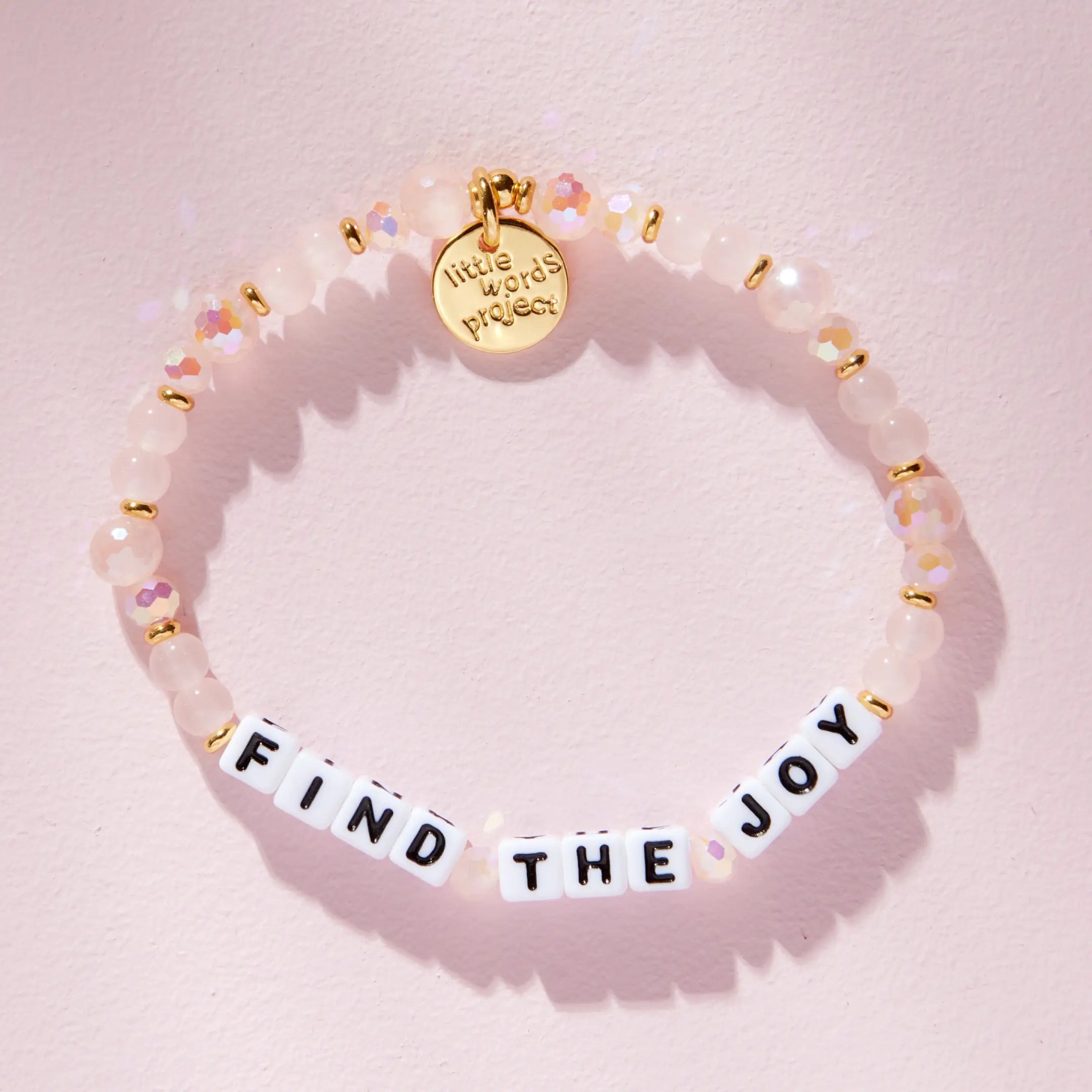 Find The Joy pink beaded bracelet, flat lay on pink