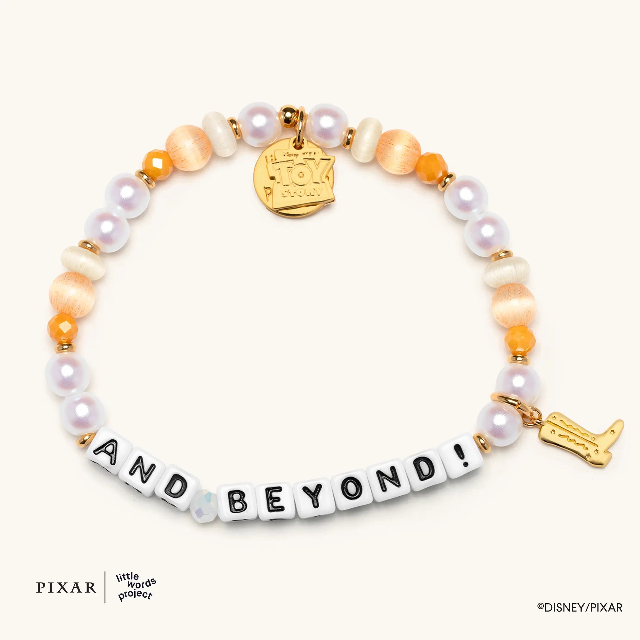 And Beyond! Toy Story bracelet, white, purple and orange beads spelling AND BEYOND with a gold charm and gold rocket charm, flat lay