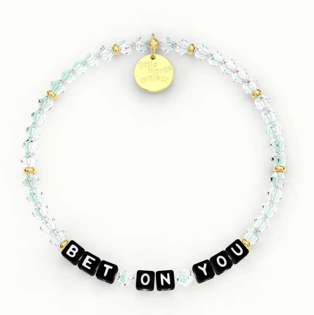 Bet On You giveback bracelet in the Clear Crystal bead pattern, black letter beads with clear and mint crystal beads with gold accents, flat-lay on cream background